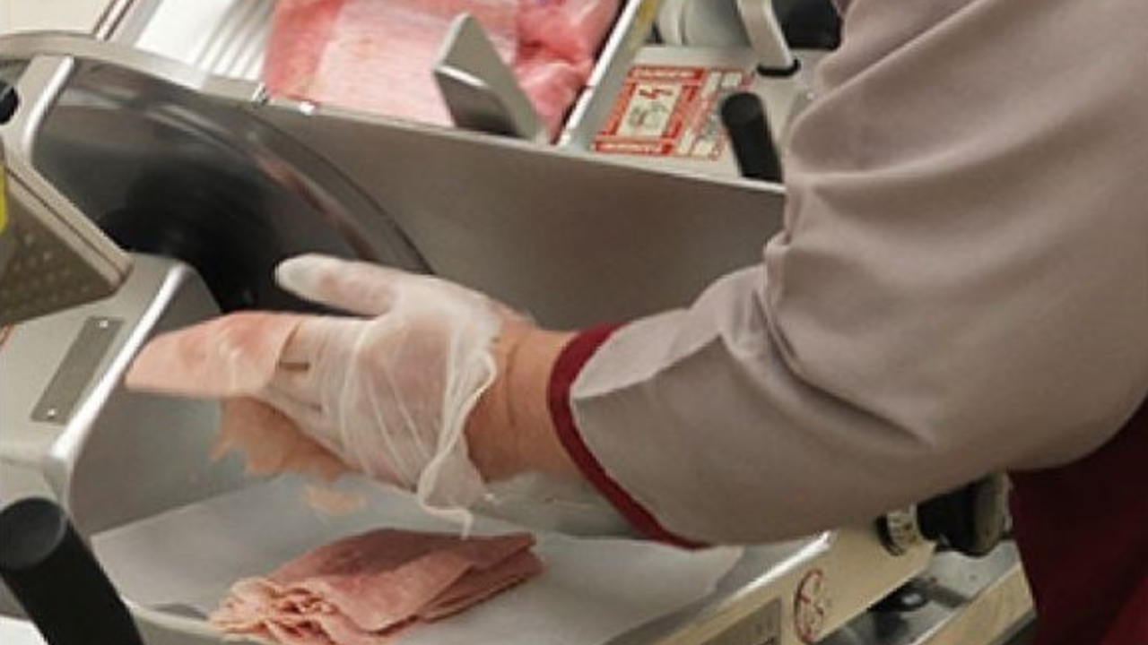 A worker slicing deli meat